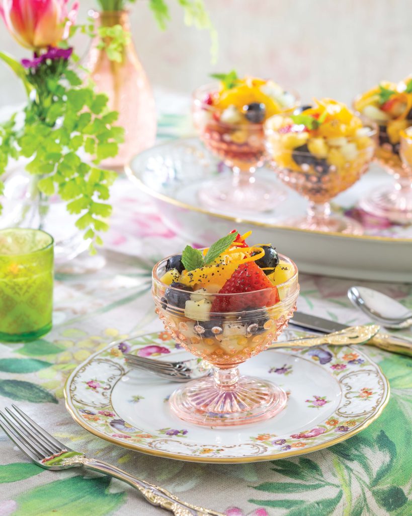 Sitting atop a floral plate, a compote made from blush-toned glass spills with fresh berries and more in our Springtime Fruit Salad.