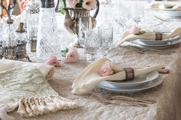 A formal table is set with elegant china, crystal, and Busatti linens in creamy shades of ivory.