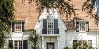 Lush vegetation welcomes guests to Leslie Saeta’s white shingled house in Southern California. A black front door and matching shutters are classic design elements that complement this early twentieth-century home.