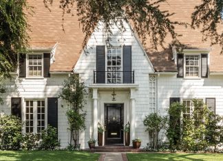 Lush vegetation welcomes guests to Leslie Saeta’s white shingled house in Southern California. A black front door and matching shutters are classic design elements that complement this early twentieth-century home.