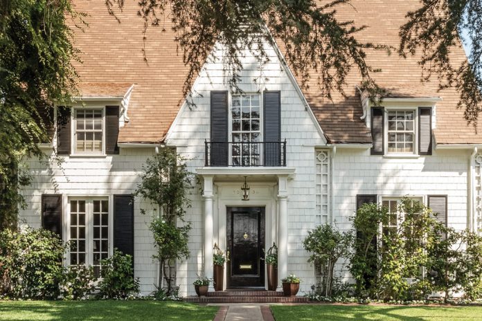 Lush vegetation welcomes guests to Leslie Saeta’s white shingled house in Southern California. A black front door and matching shutters are classic design elements that complement this early twentieth-century home.