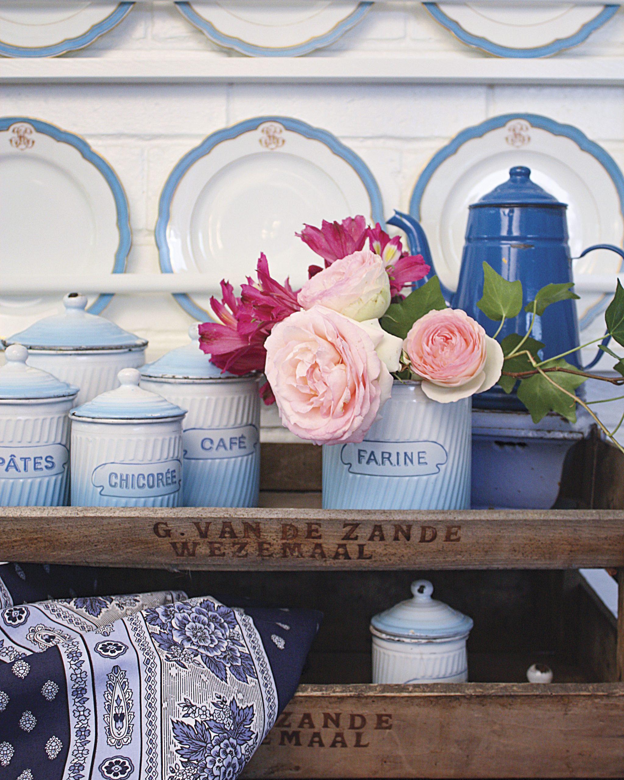 Blue and white wide jars sit atop antique crates, filled to the brim with pink flowers.