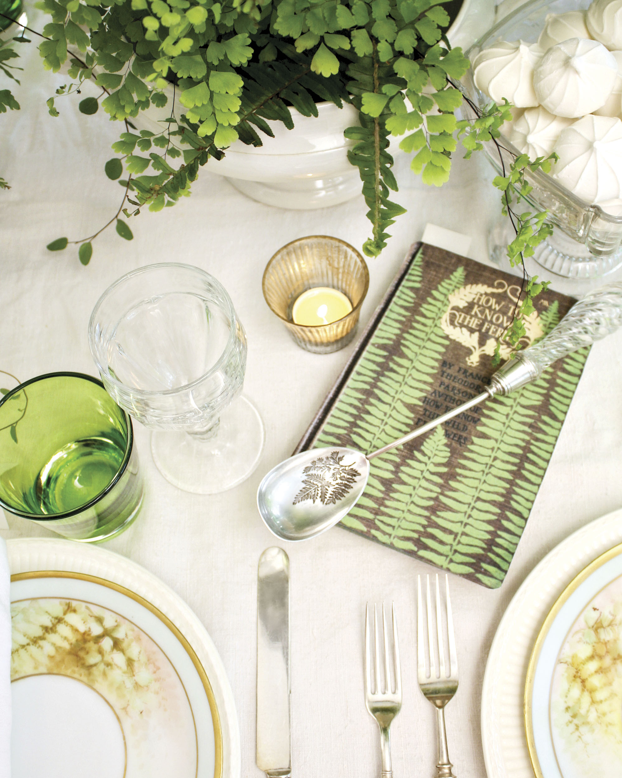 A green-and-white table setting is dressed with unique silver. This spoon bears the image of a fern frond.