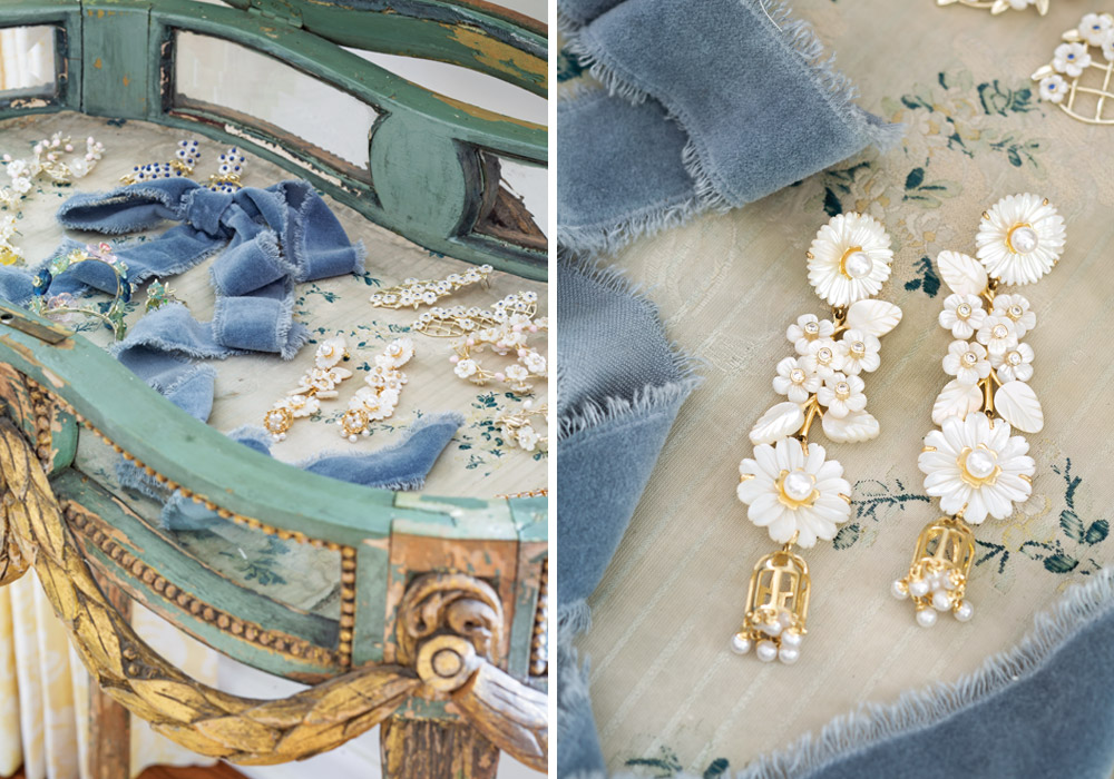 An antique glass-top table displays glittering earrings from Nicola Bathie Jewelry with floral and pearl details.