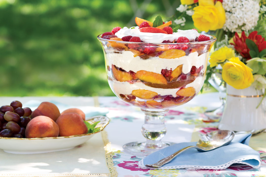  Outdoor table set with a glass trifle bowl filled with Peach-Melba-and-Sabayon Trifle.