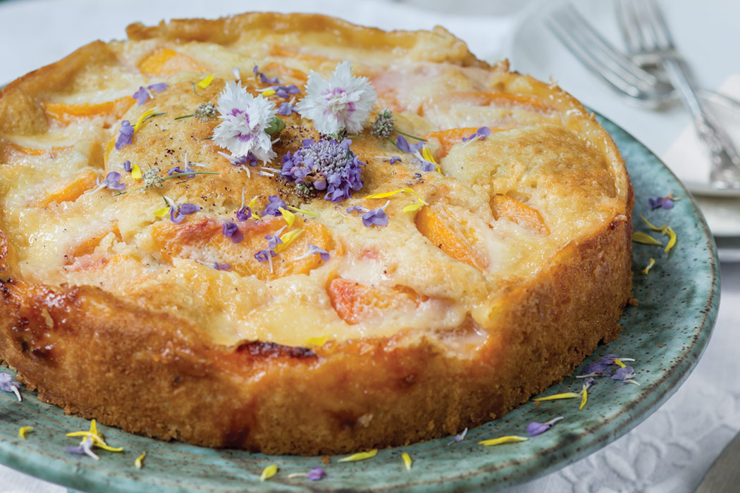 Peach Kuchen garnished with purple and white edible flowers.
