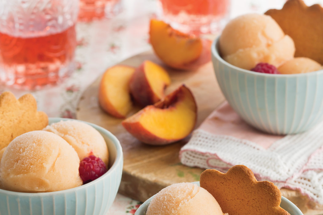 Blue bowls of Peach-Rosé Sorbet topped with gingersnaps and raspberries. 
