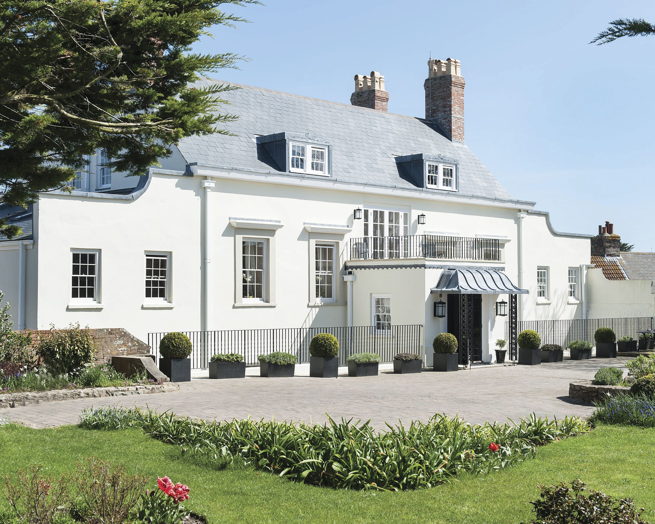 The exterior of the Georgian home is as breathtaking as inside, with multiple chimneys, a balcony, and well-kept greenery.