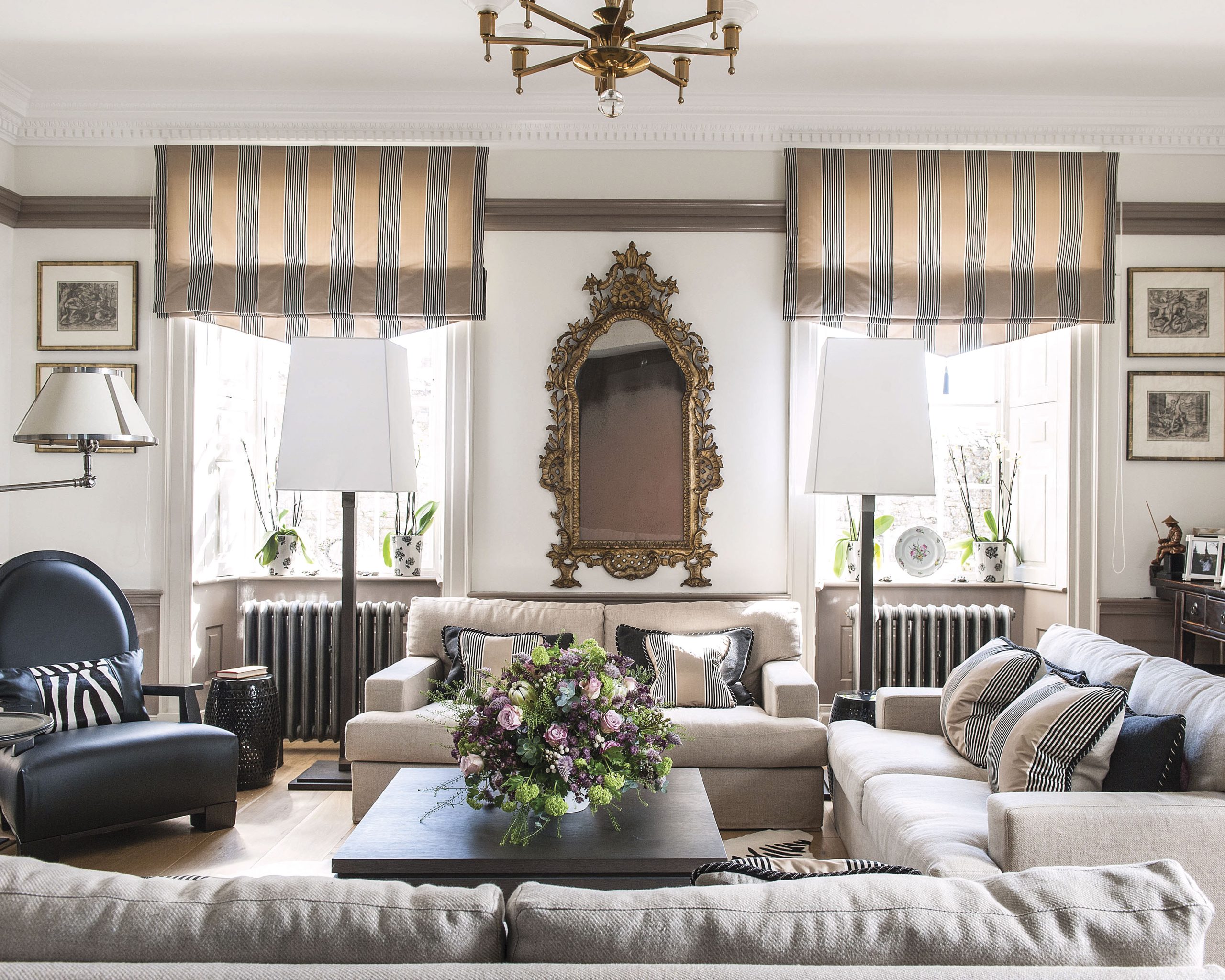 The living room, though brushed with black accents, remains bright thanks to large windows and neutral shades throughout.