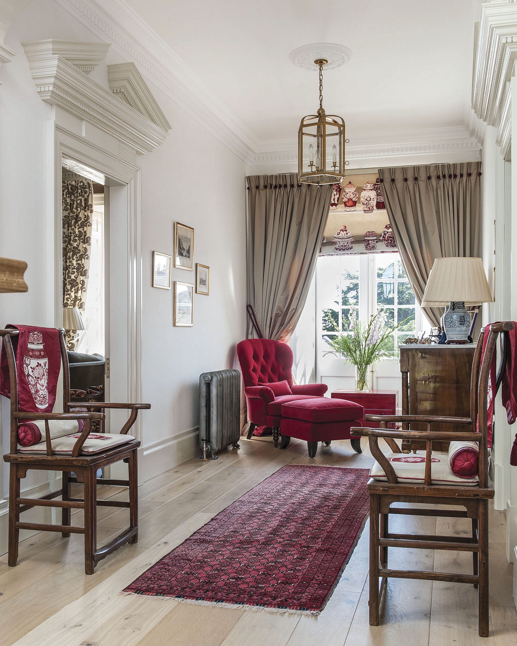The hallway exudes elegance thanks to custom crown moulding, a lovely runner, and a velvet chaise lounge by the window.