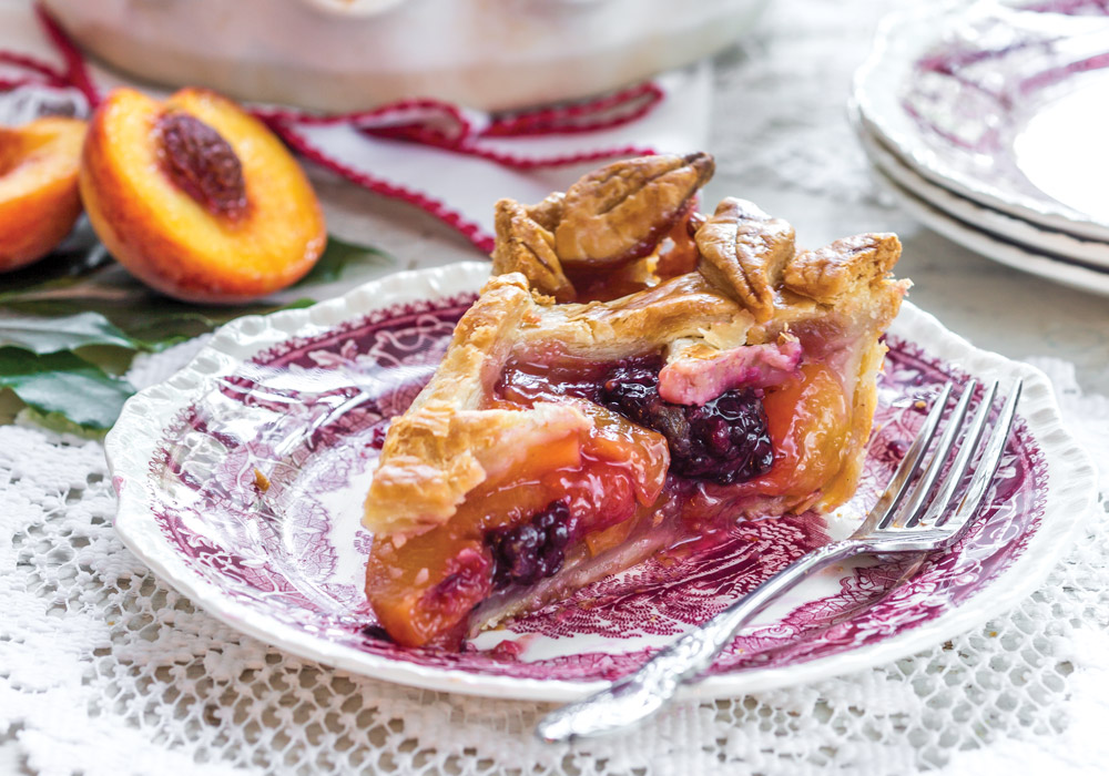 Slice of Peach-Blackberry Pie on burgundy patterned plate with a silver fork.