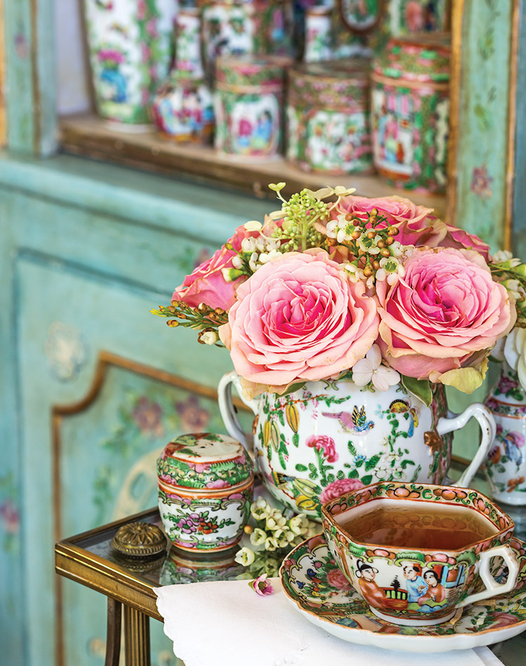 Rose medal vase full of peonies and roses, beside an inviting cup of tea served in rose medal on accompany saucer.