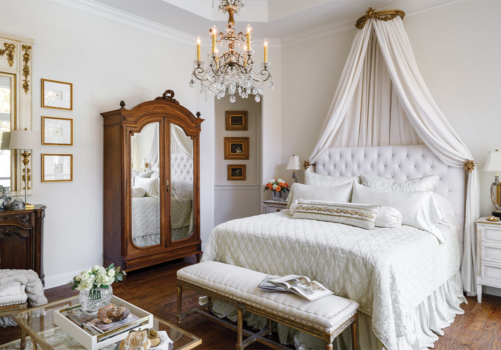 Kristie Shelton’s primary bedroom is filled with her collected treasures, including a glass-front armoire and another antique crystal lighting fixture.