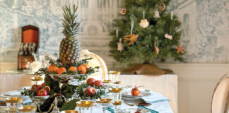 Jenny Bohannon’s dining room features a Christmas tablescape. Green-trimmed Julie Amory linens cover the table laid with Mottahedeh’s Duke of Gloucester china and gold-rimmed glassware. Fresh fruit and greenery in silver holders make up the centerpieces.