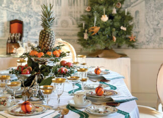 Jenny Bohannon’s dining room features a Christmas tablescape. Green-trimmed Julie Amory linens cover the table laid with Mottahedeh’s Duke of Gloucester china and gold-rimmed glassware. Fresh fruit and greenery in silver holders make up the centerpieces.