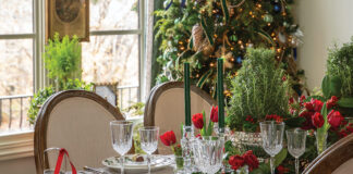 Crystal for Christmas: Crystal wine and water goblets are set on a dining table decorated for a holiday party. A decorated Christmas tree twinkles behind the table.