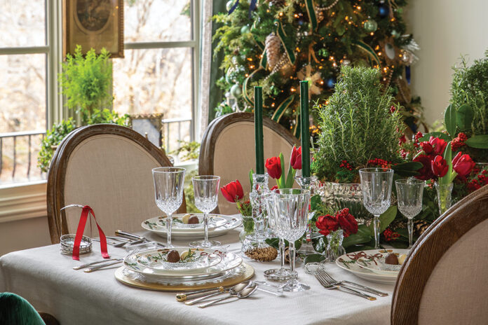Crystal for Christmas: Crystal wine and water goblets are set on a dining table decorated for a holiday party. A decorated Christmas tree twinkles behind the table.