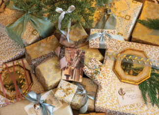 A mingling of blue, gold, and ivory wrapping adorn the cache of presents beneath one pastel tree this Christmas.