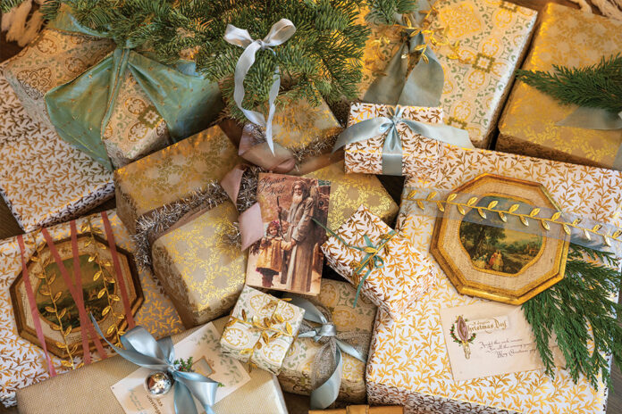 A mingling of blue, gold, and ivory wrapping adorn the cache of presents beneath one pastel tree this Christmas.
