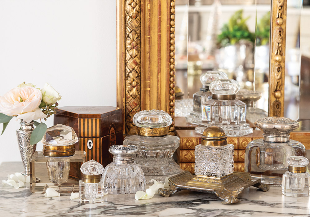 A collection of crystal ink wells is displayed atop a marble surface, adding storied charm to the space.
