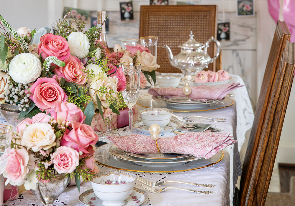 This table is set for a Valentine’s Day gathering, complete with pink roses and sweet cards hanging from the mantel.