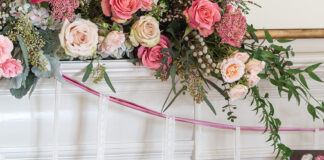 A lush arrangement of pink and white roses is nestled atop the mantel with a pretty garland made by hanging Valentine cards from wisps of ribbon.