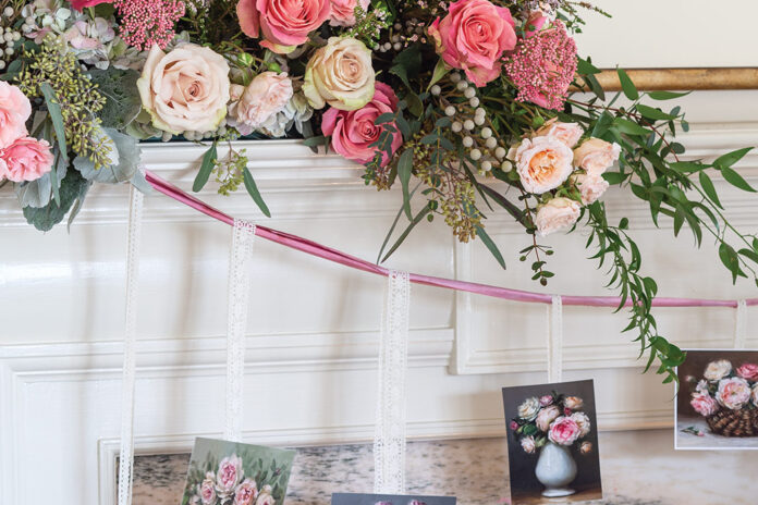 A lush arrangement of pink and white roses is nestled atop the mantel with a pretty garland made by hanging Valentine cards from wisps of ribbon.