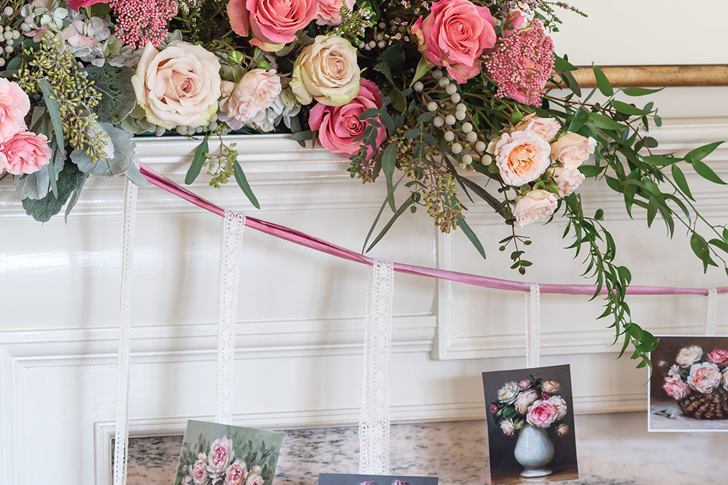 A lush arrangement of pink and white roses is nestled atop the mantel with a pretty garland made by hanging Valentine cards from wisps of ribbon.