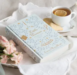 Enjoy discussion questions for Little Women, seen here nestled between pink roses and a cup of tea with shortbread cookies.