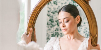 Wedded Bliss: 9 Ways to Add Romance to Your Wedding Events. A lovely bride clad in a delicate lace gown gazes into a gilt-edged mirror.