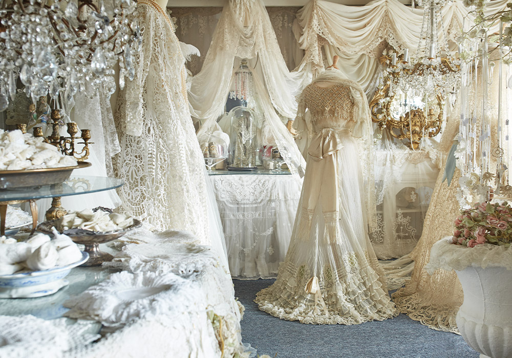 Lace in every imaginable shade of white drapes from ceiling to floor like tiers of frosting on a wedding cake, while crystal chandeliers and strings of pearls catch the sunlight pouring through the front windows of Sheelin Lace shop.