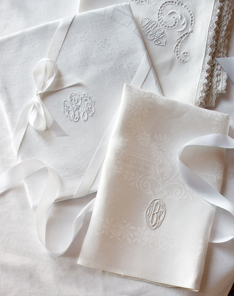 An exquisite collection of ivory monogrammed linens is carefully folded and tied with a sweet satin ribbon.