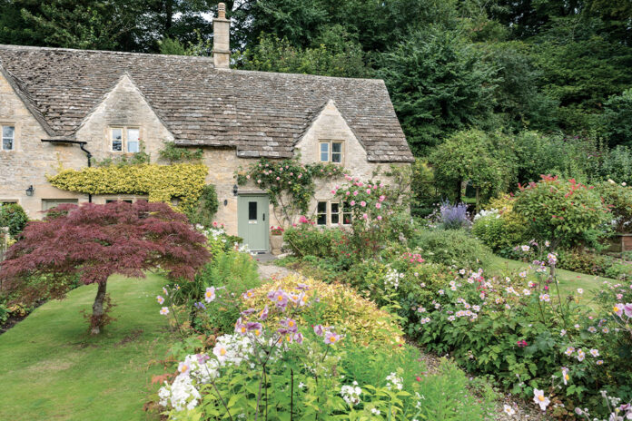 Preview Our Inviting English Cottage 2024 Special Issue: The walkway to the front door of this English cottage is lined with a profusion of flowers.