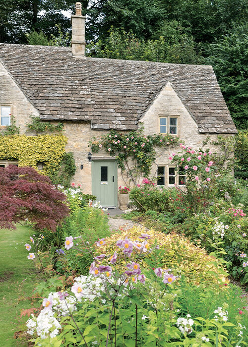 The walkway to the front door of this English cottage is lined with a profusion of flowers.