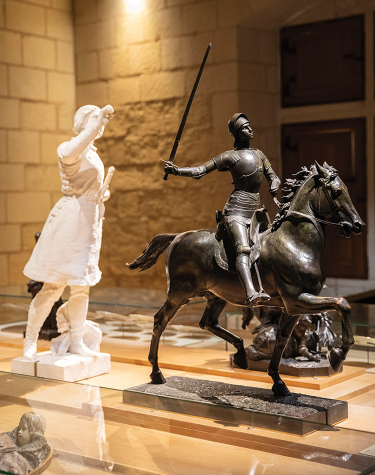 Dark metal statue of Joan of Arc on horseback.