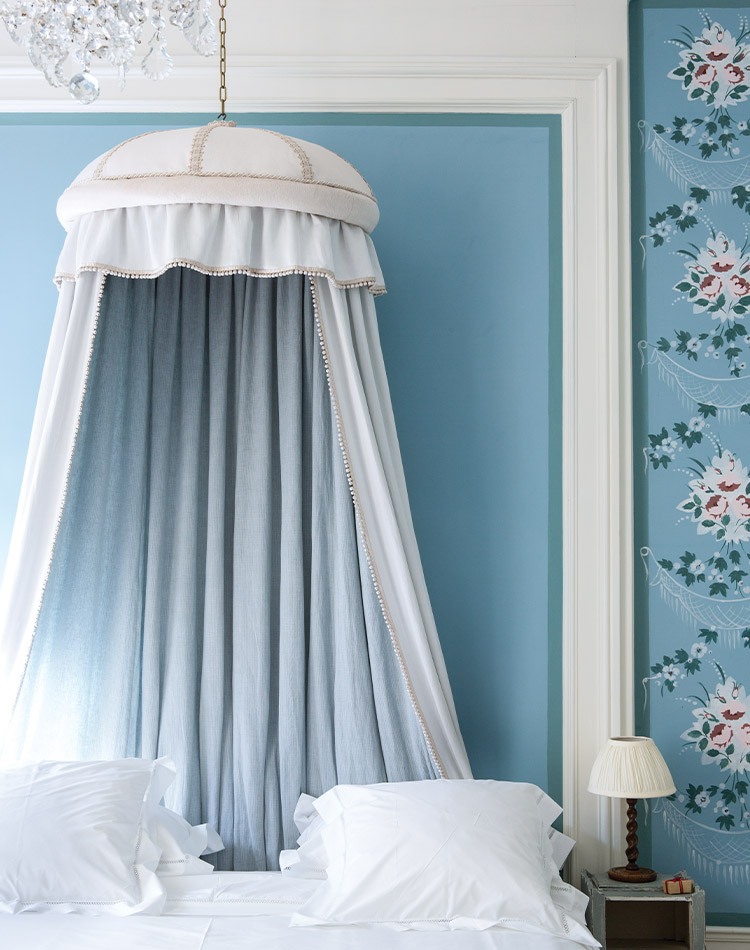 Blue walls and a white canopy dress this blue-and-white French bedroom in a dreamy atmosphere.