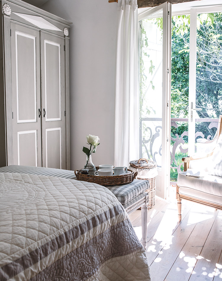 The calming gray tones of this bedroom open out onto a bright, breezy world through a floor-to-ceiling window.