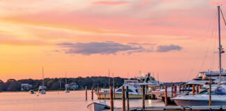 The sky turns a shade of salmon pink at sunset in this serene harbor.