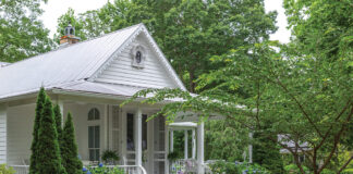 A white cottage overlooks a lush green lawn in our Romantic Cottage 2024 issue.