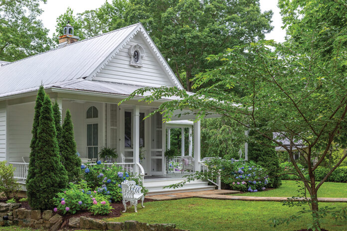 A white cottage overlooks a lush green lawn in our Romantic Cottage 2024 issue.