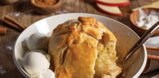 Two scoops of vanilla ice cream and a perfectly golden brown baked Apple Dumpling are served at this fall table.
