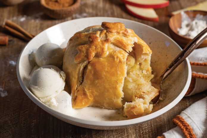 Two scoops of vanilla ice cream and a perfectly golden brown baked Apple Dumpling are served at this fall table.