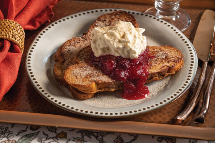 A serving of cinnamon French toast with cranberry compote and crème fraiche whipped cream bring autumnal charm to the breakfast table.