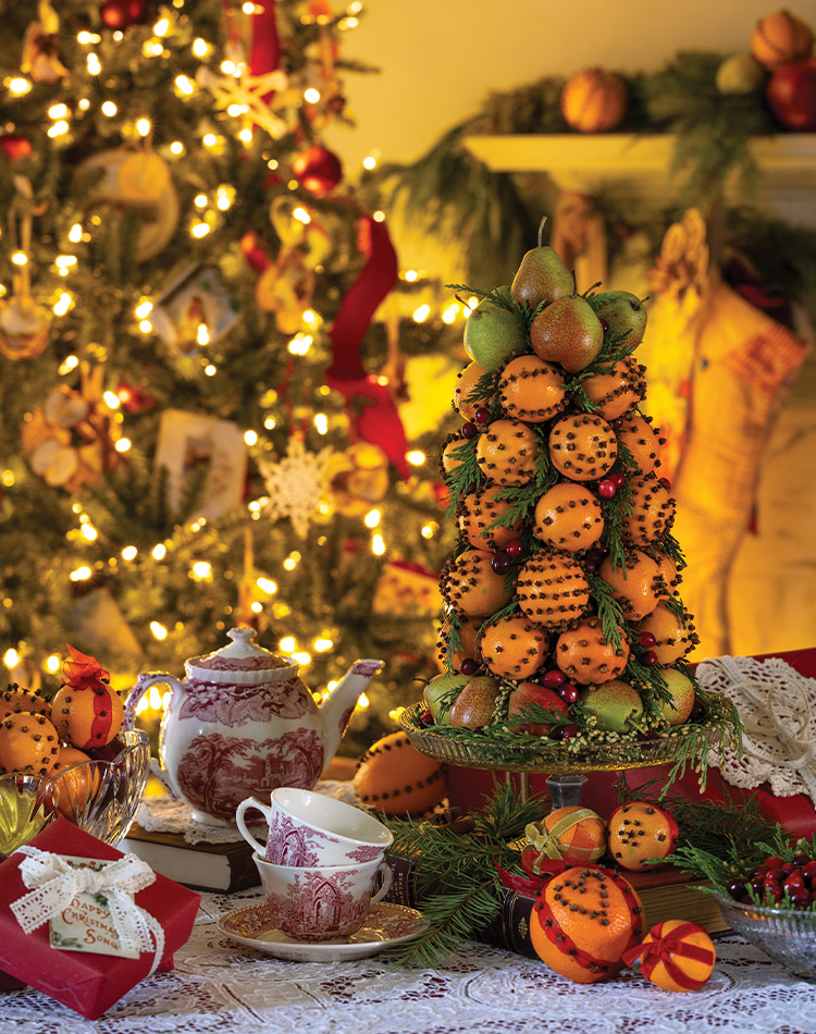 Ornaments of dried fruit and oranges studded with cloves lend homespun charm to this Little Women inspired Christmas gathering.
