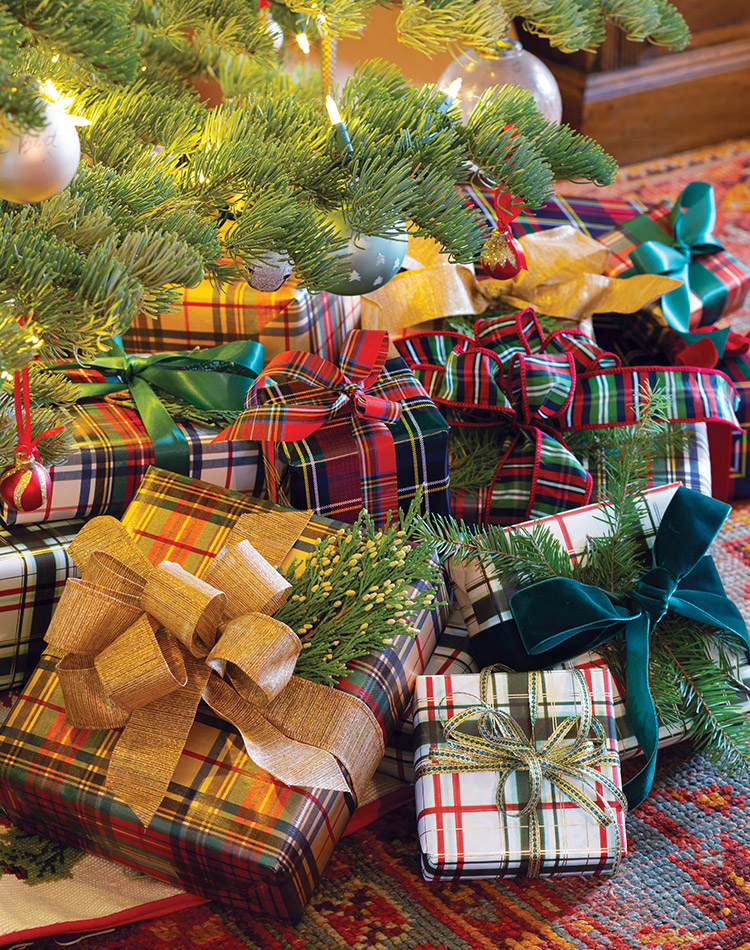 A slew of Christmas gifts, all wrapped in tartan paper and ribbon, are gathered beneath the tree.