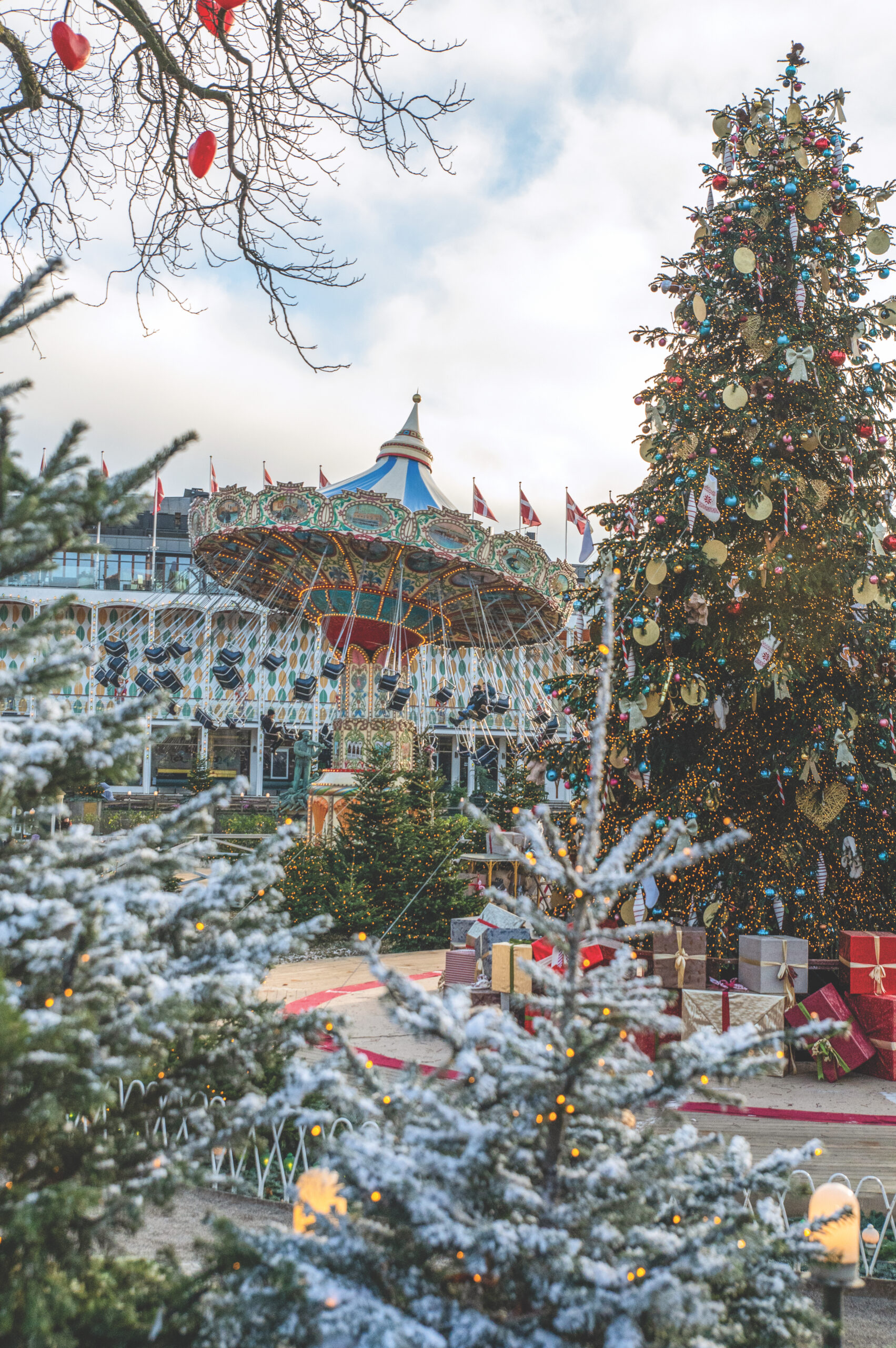 Tivoli Gardens bedecked for Christmas, with a towering Christmas tree and trees covered in frost framing amusement rides.