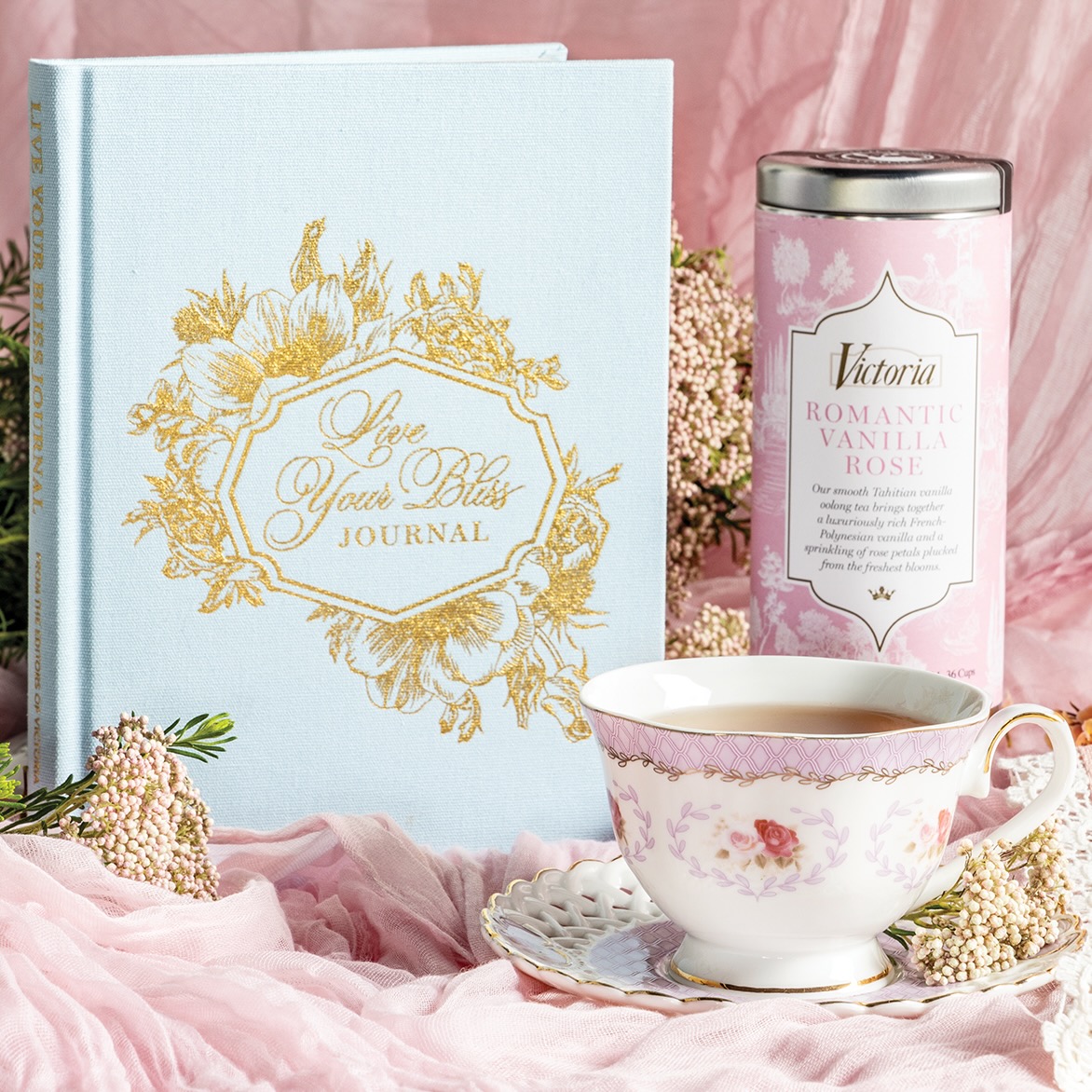 The Victoria Live Your Bliss journal with a canister of tea and a cup of tea on a saucer.