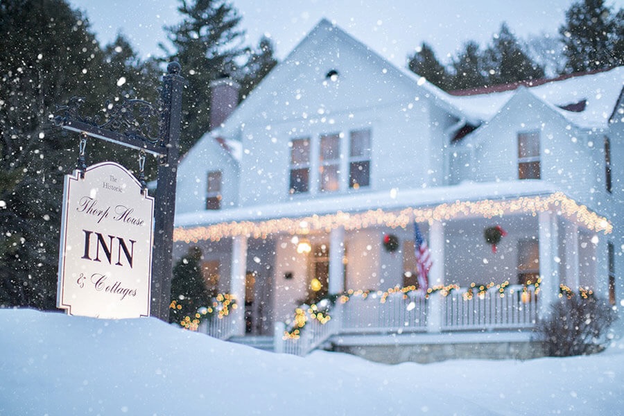 Exterior of the main building at The Thorp House Inn in wintertime with snow covering the lawn