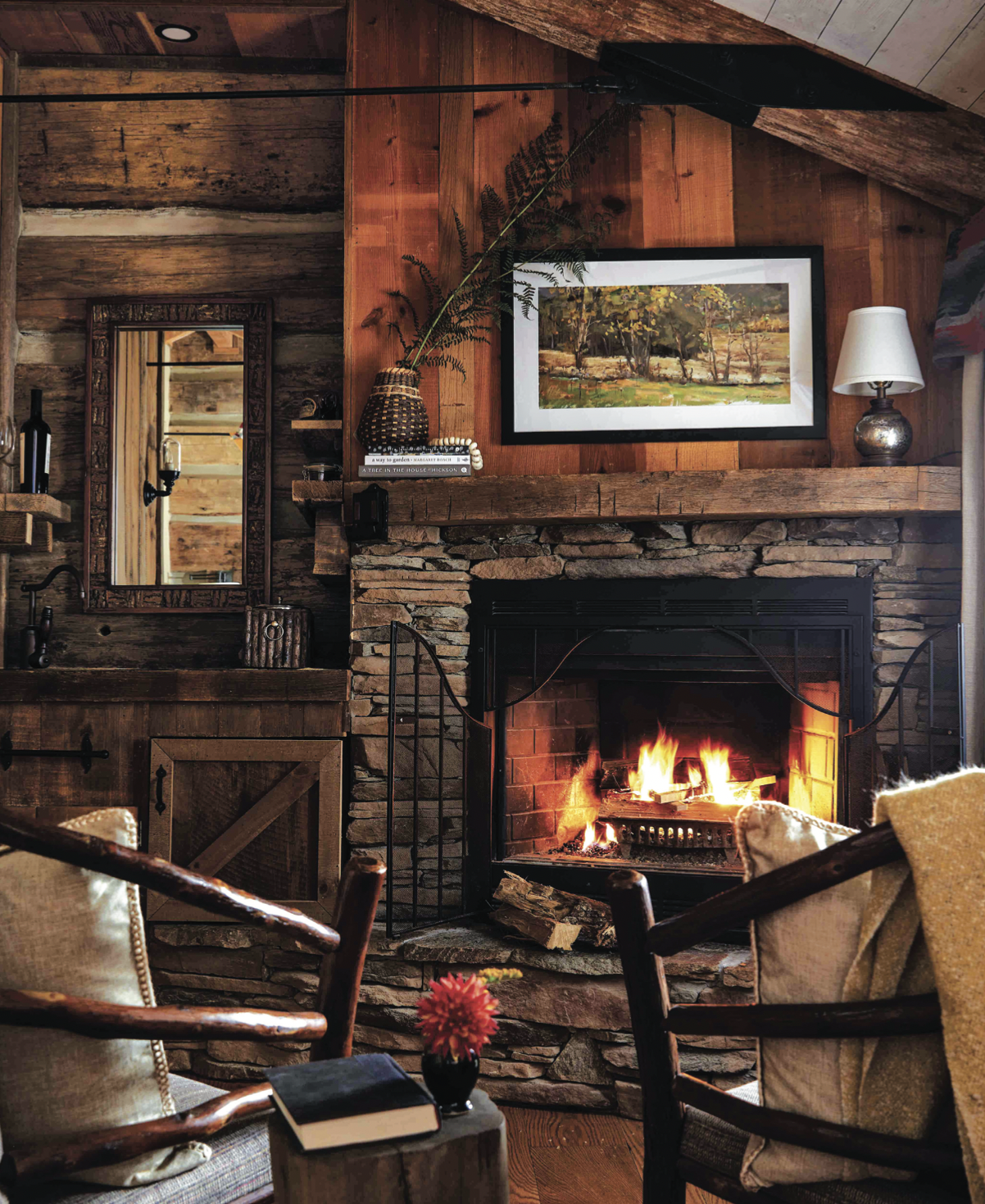 A fire roars in a fireplace, surrounded by wood paneled walls and rustic furniture.