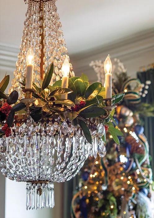 A crystal chandelier accented with fresh magnolia leaves.